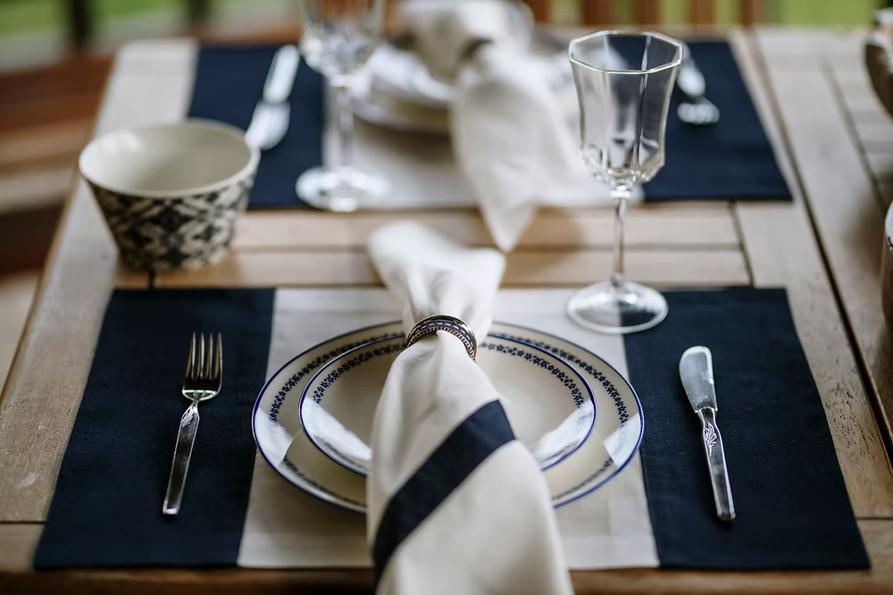 22 Maggio Istanbul Marinaio Linen Napkin Set of 4-Dining table setting with plates, cutlery, and glasses on a wooden table.