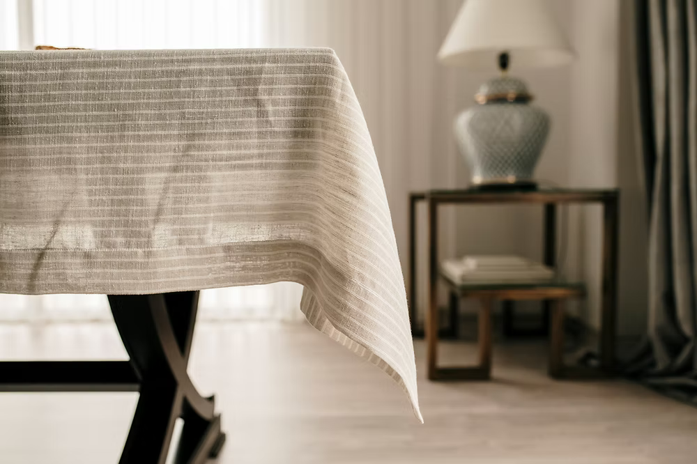 22 Maggio Istanbul Suolo Linen Tablecloth-Tablecloth on a table with a blurred background featuring a lamp and books.
