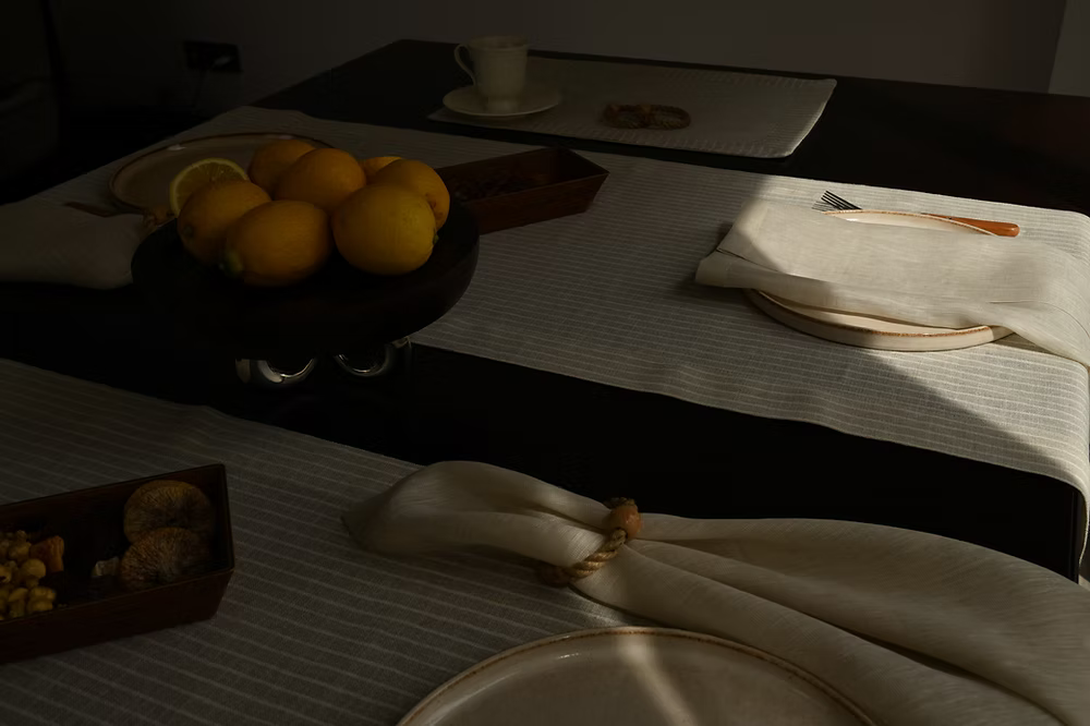 22 Maggio Istanbul Terreno Beige Linen Napkin Set of 4-Dining table setting with lemons on a plate, cutlery, and a napkin.