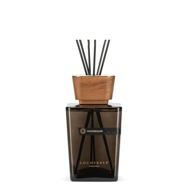 A Mannequin brand diffuser with a wooden lid and black sticks, containing a amber, spicy, warm aroma with hints of pink pepper and bergamot.