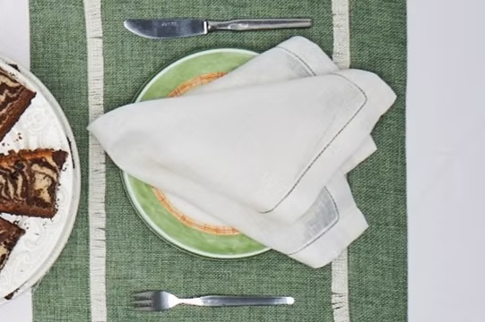 Amalfi Linen Napkin Set of 4-Green plate with a folded white napkin on a green placemat, with brownies on a side plate.