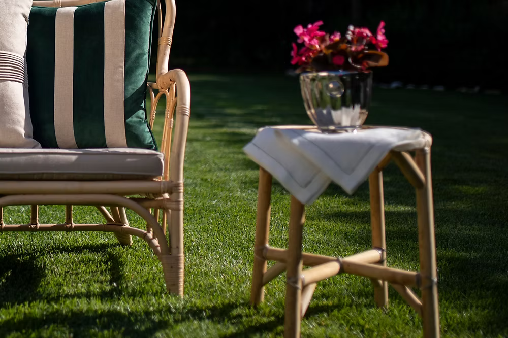 Amalfi Linen Napkin Set of 4-Wicker chair with striped cushions and a small table with flowers on a grassy area
