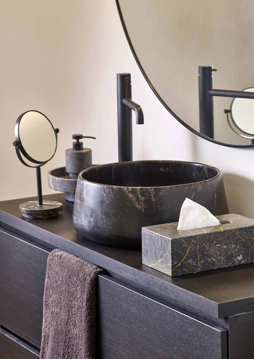 Bathroom vanity with black marble sink, faucet, and accessories.