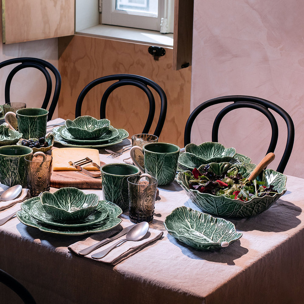 Bordallo Pinheiro Cabbage Chip & Dip Bowl-Dining table set with green leaf-patterned dishes and utensils in a home setting.
