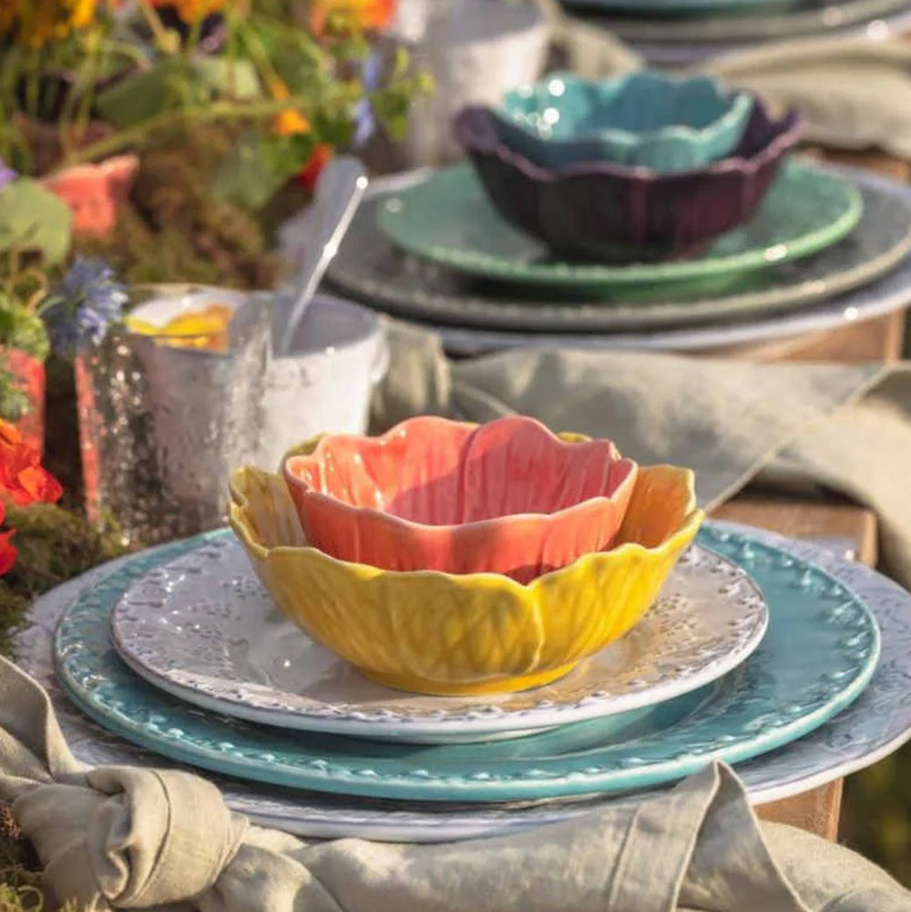 Bordallo Pinheiro Flora Bowl-Colorful ceramic bowls and plates on a table with a garden background