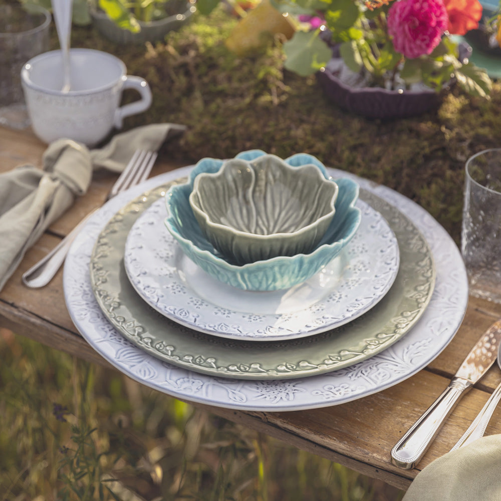 Bordallo Pinheiro Flora Dessert Plate-Set of ceramic plates and bowls on a wooden table with a natural outdoor background