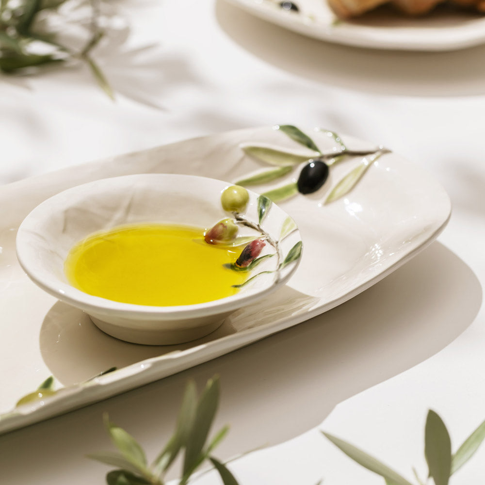 Bordallo Pinheiro Olival Small Bowl-White dish with olive oil and olives on a white surface with olive branches.