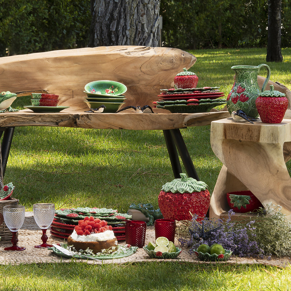 Bordallo Strawberries Bowl – Artisan Fruit Ceramic UAE-Outdoor setting with a wooden table and decorative items on a grassy background