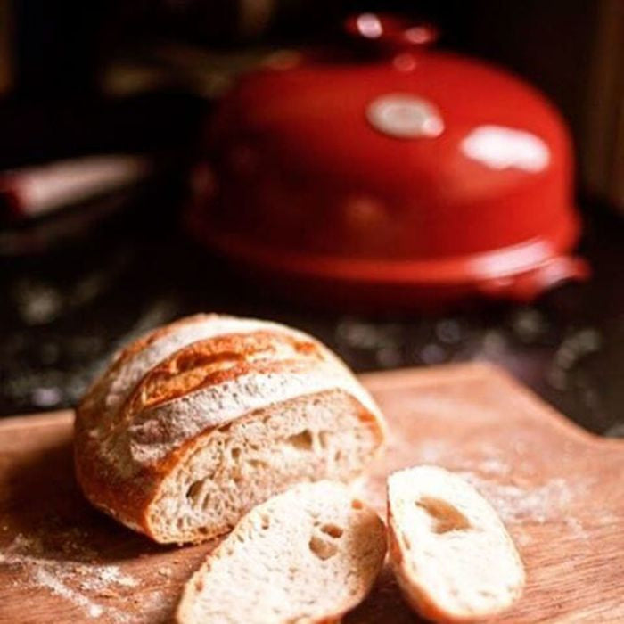 Emile Henry Bread Baker-Sliced bread on a wooden cutting board with a red pot in the background