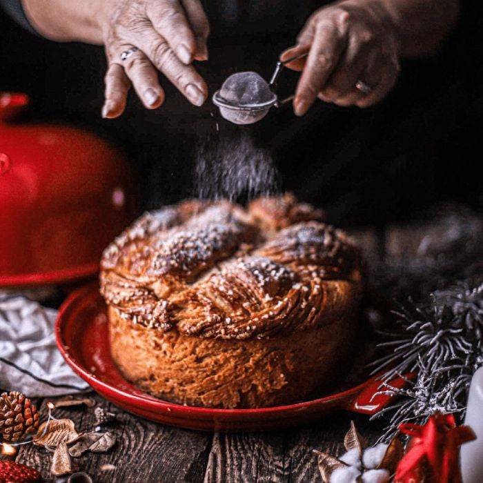 Emile Henry Bread Baker-Baked dish being dusted with powdered sugar on a festive background