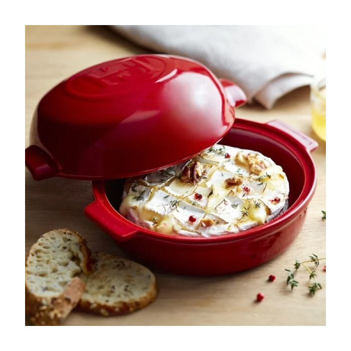 Emile Henry Cheese Baker-Red cheese fondue pot with a wheel of cheese and bread on a wooden surface