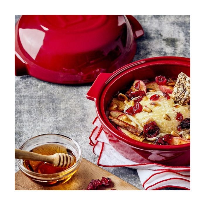 Emile Henry Cheese Baker-Red ceramic dish with dessert, honey dipper, and red teapot on a gray surface
