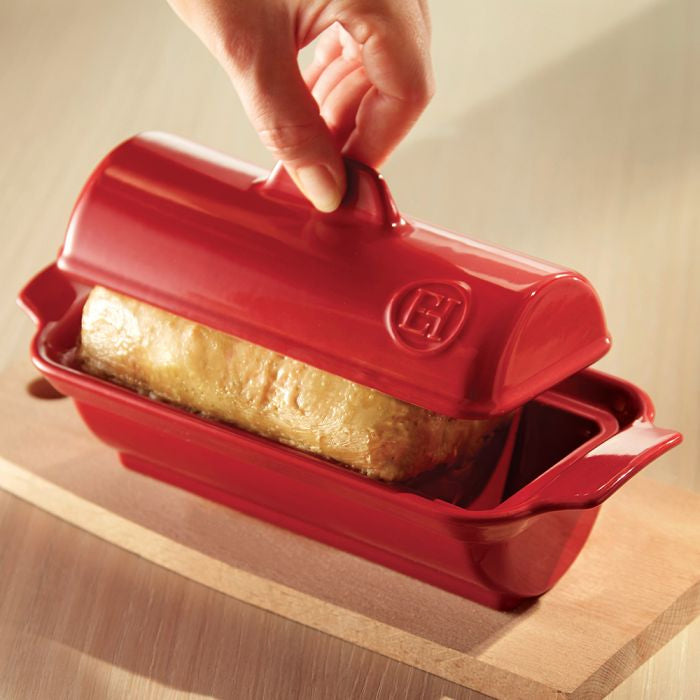 Emile Henry Foie Gras Medallion Terrine-Red bread loaf pan with a loaf of bread inside, held by a hand.