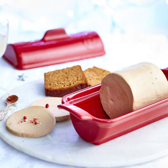 Emile Henry Foie Gras Medallion Terrine-Red terrine with foie gras on a white plate with crackers and a spreader