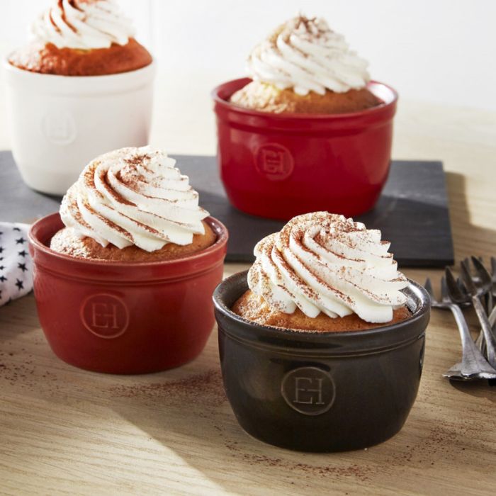 Emile Henry Ramekin, 10cm-Four small desserts in red and black ramekins with whipped cream on a wooden surface.