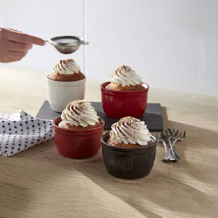 Emile Henry Ramekins, Set of 2-Four small dessert bowls with whipped cream on a wooden surface, with a hand using a sieve.