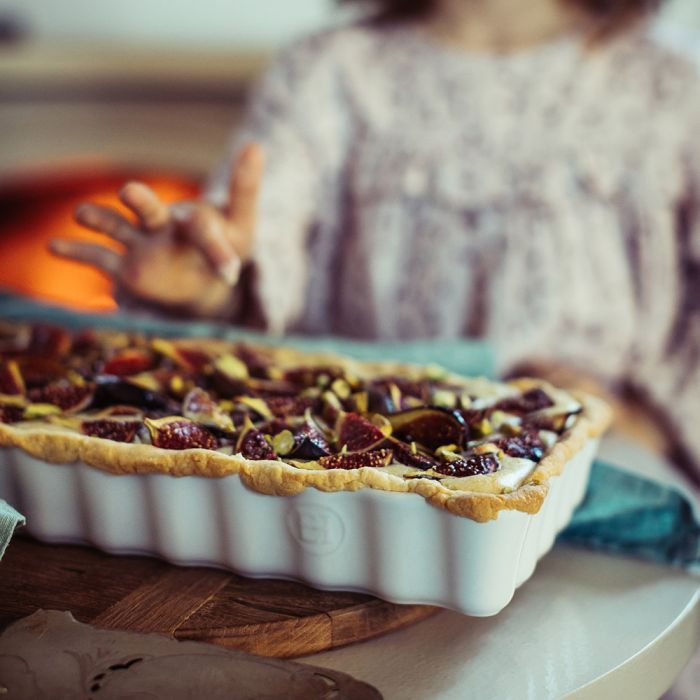 Emile Henry Slim Rectangular Tart Dish-Pie in a white dish on a table with a person in the background
