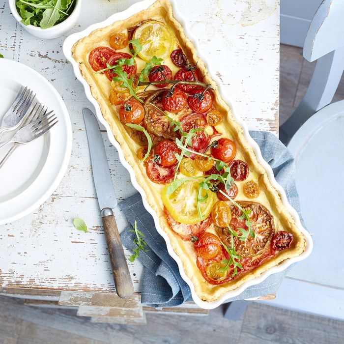 Emile Henry Slim Rectangular Tart Dish-Tomato tart on a wooden table with plates and cutlery