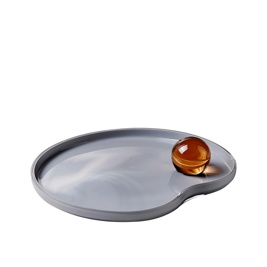 Gray oval tray with a round amber-colored object on a white background