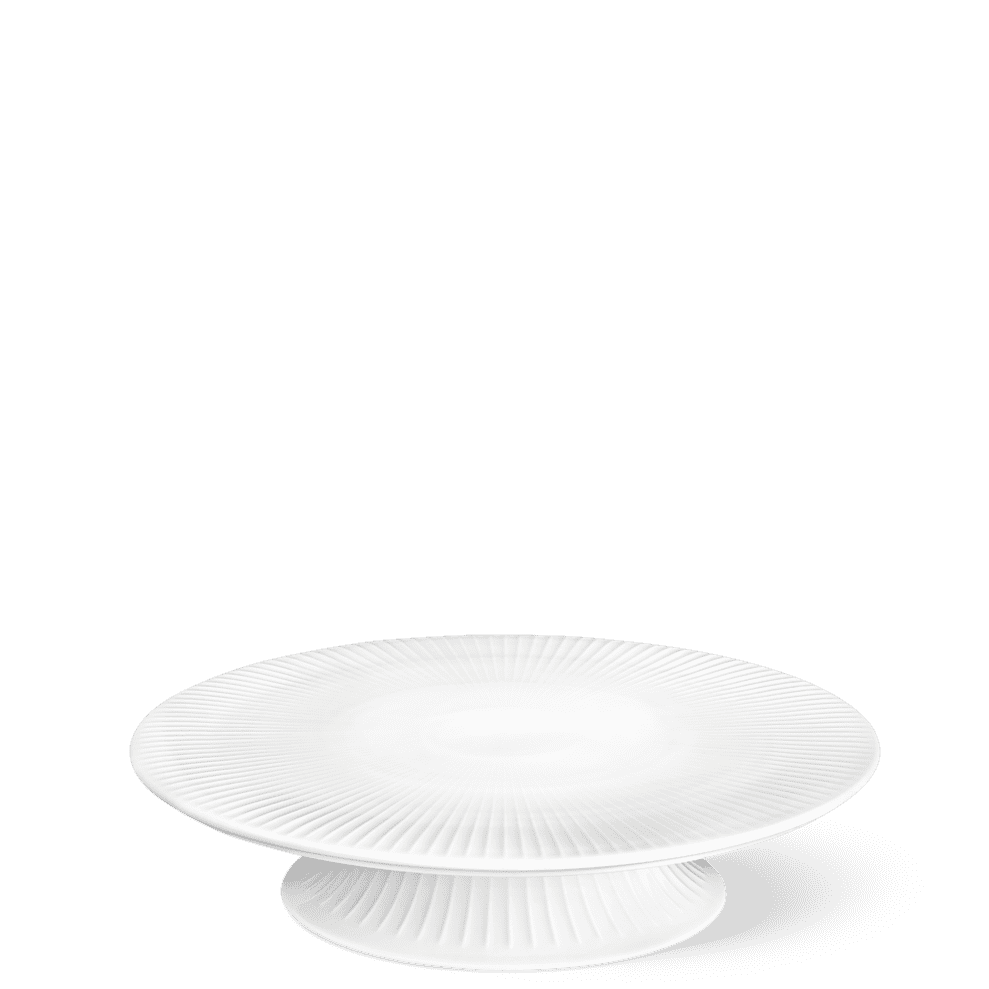 White ceramic cake stand on a green background