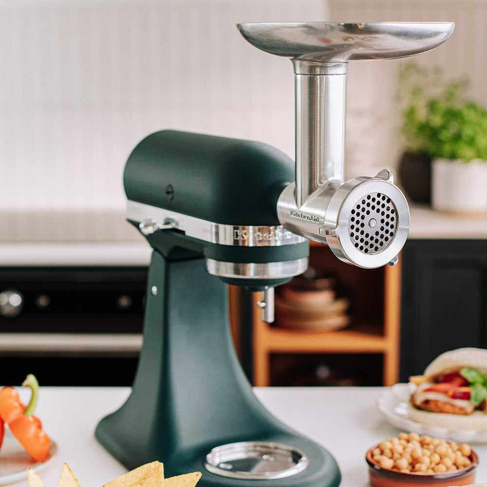 KitchenAid Green kitchen stand mixer with meat grinder attachment in a kitchen setting
