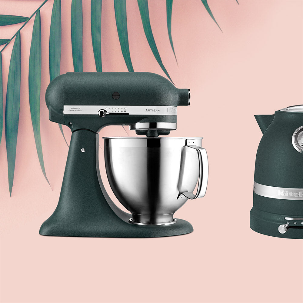 KitchenAid Green stand mixer and kettle on a pink background with green leaves.
