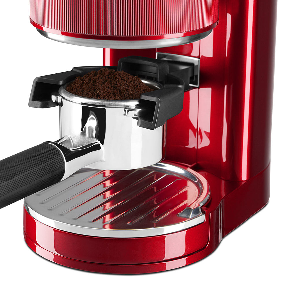 Red espresso machine with a focus on the filter basket and ground coffee.