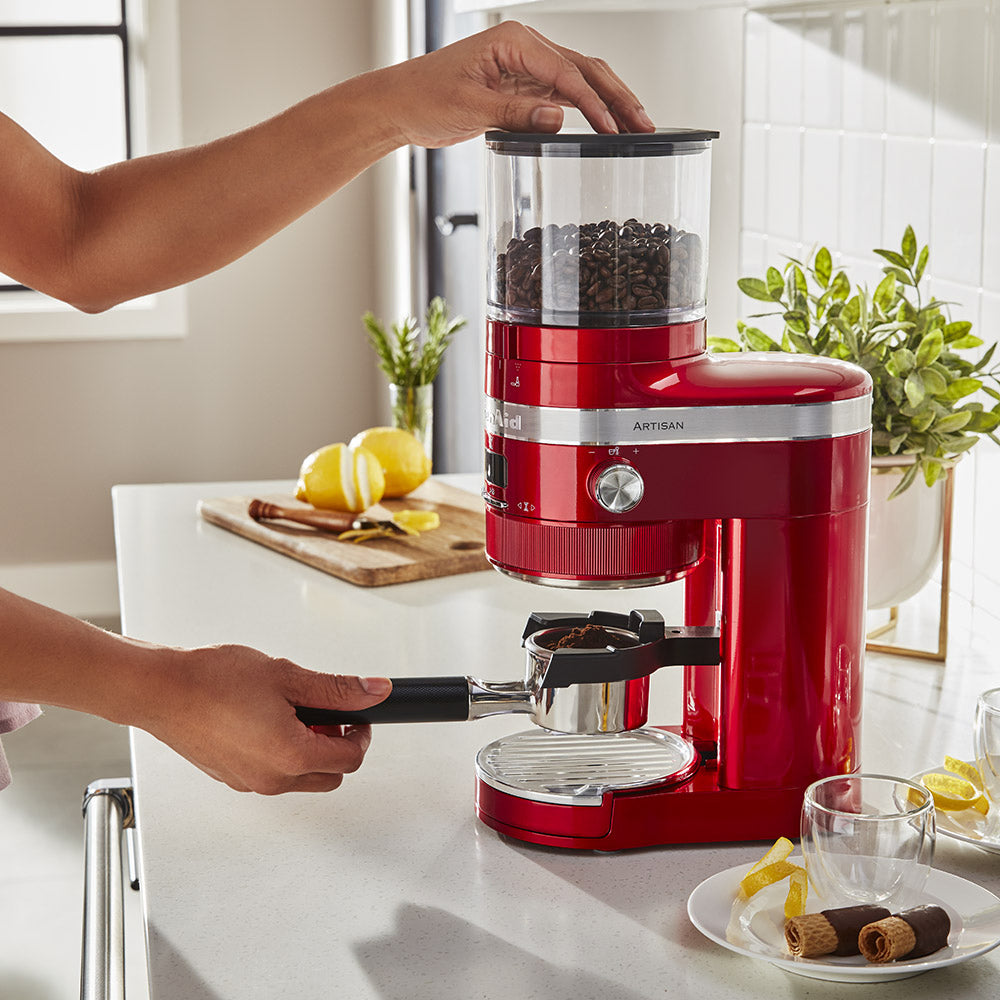 Red espresso machine being used in a kitchen setting with a person operating it.