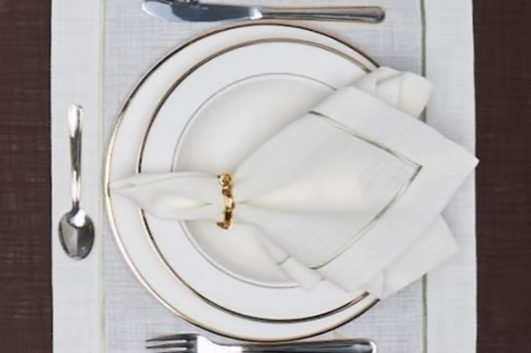 Lusso Dinner Napkin Set of 4-Elegant table setting with white plates, silverware, and folded napkin on a textured surface.