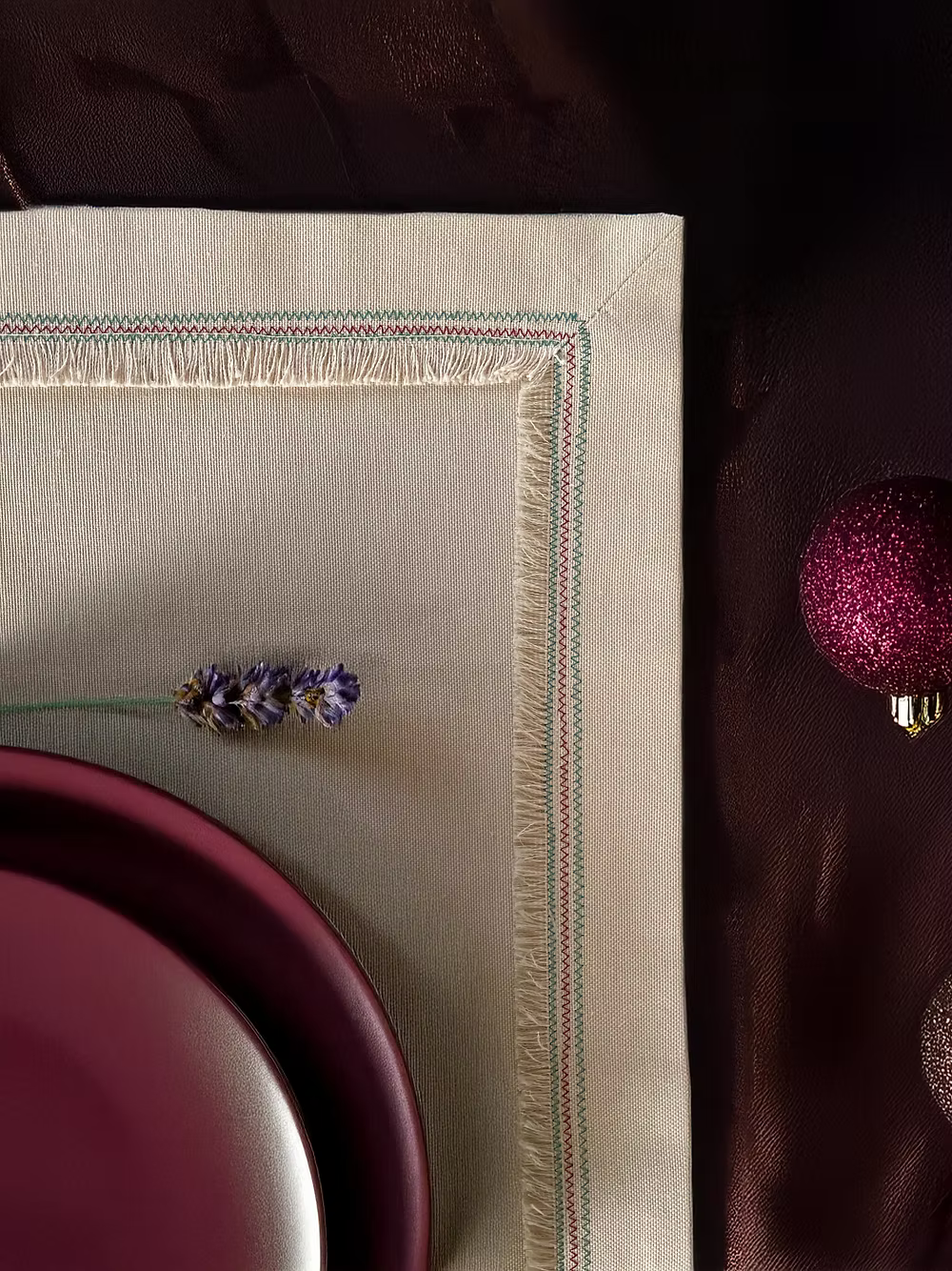 Nappina Placemat Set of 4-Beige napkin with floral embroidery on a dark surface