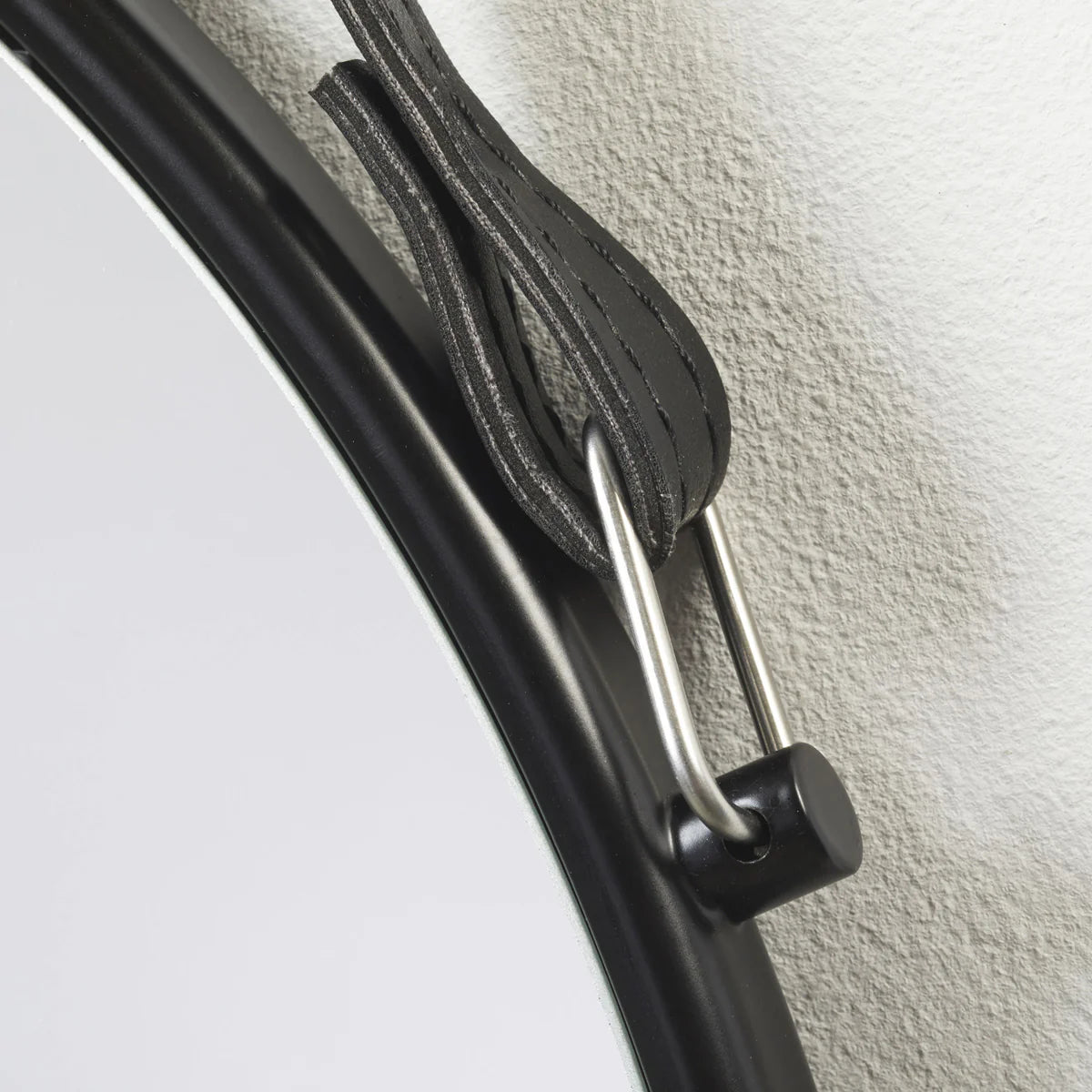 Close-up of a carabiner attached to a metal bar on a textured surface