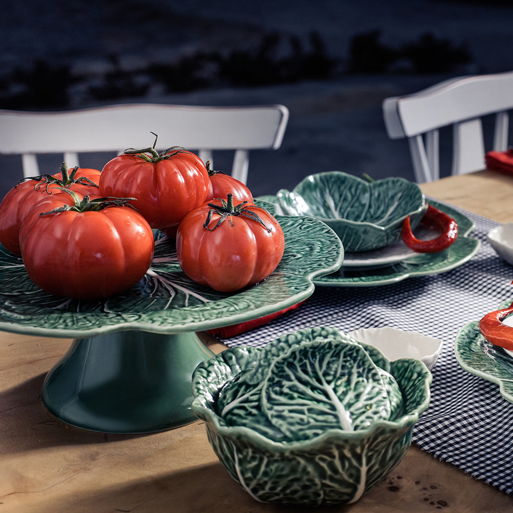 Ceramic plates and bowls with leaf design on a table outdoors.