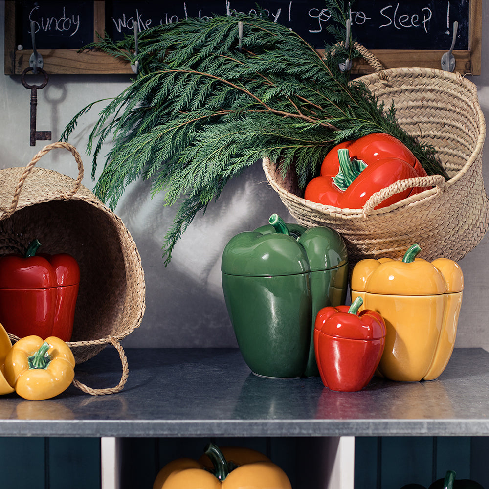 Colorful ceramic pepper containers on a kitchen counter with a chalkboard wall in the background.