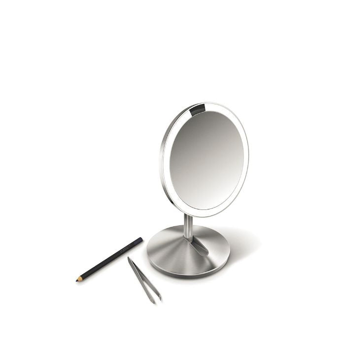 Simplehuman Sensor Mirror Fold with Travel Case-Silver makeup mirror with a pencil and tweezers on a white background