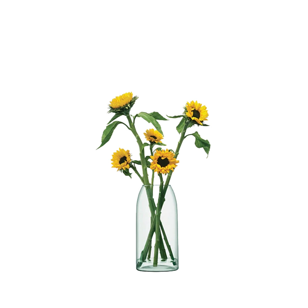 An elegant clear glass vase with a wide, gently tapered form, containing several sunflowers.