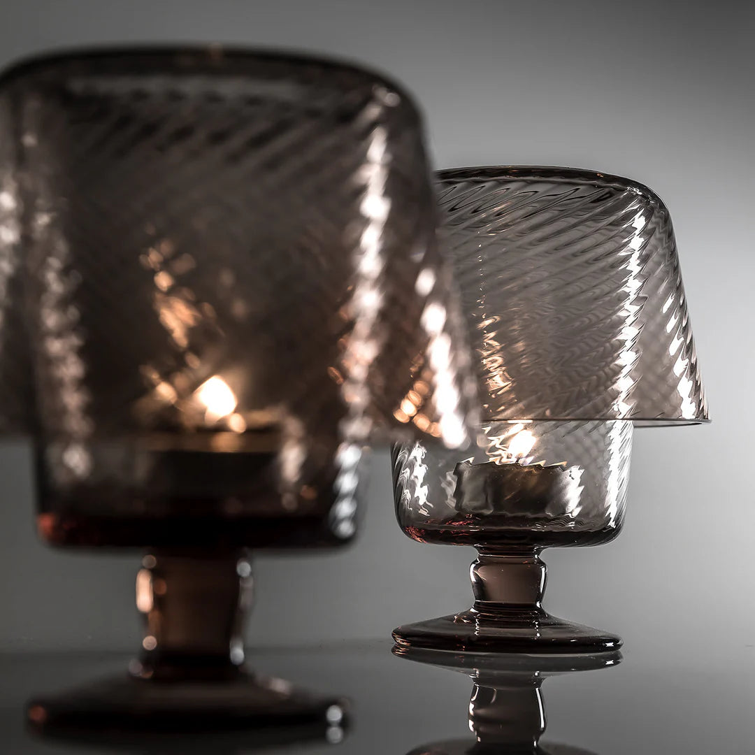 Two glass lamps with textured shades on a reflective surface.