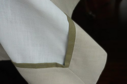 22 Maggio Istanbul Cavalcanti Designer Table Cloth-Close-up of a white fabric with green trim on a dark background