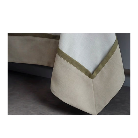 22 Maggio Istanbul Cavalcanti Designer Table Cloth-Close-up of a beige and white fabric with a green trim on a dark background
