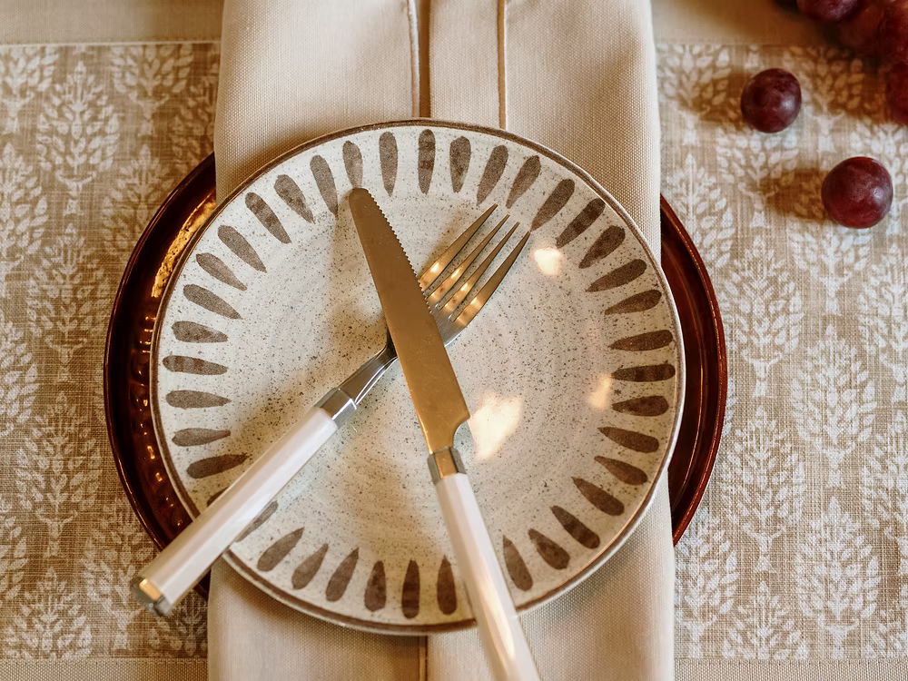 22 Maggio Istanbul Latte Placemat Set of 4-Set table with a decorative plate, knife, and fork on a patterned tablecloth.