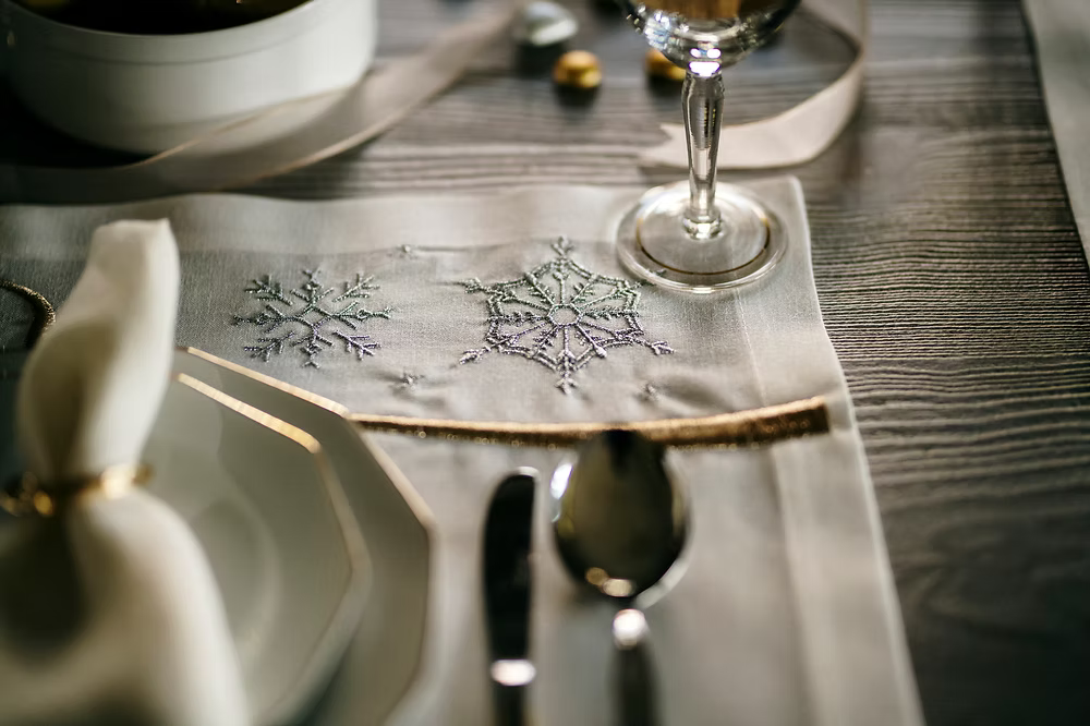 22 Maggio Istanbul Le Alpi  New Year Placemat Set of 4-Close-up of a table setting with silverware, plates, and a decorative napkin on a wooden table.