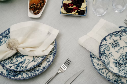 22 Maggio Istanbul Sereno Linen Napkin Set of 4-Set table with blue and white floral plates, silverware, and napkins on a gray surface.