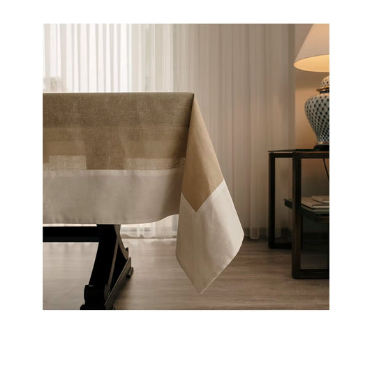22 Maggio Istanbul Terreno Linen Tablecloth-Beige and brown checkered tablecloth on a wooden table with a lamp and curtains in the background.