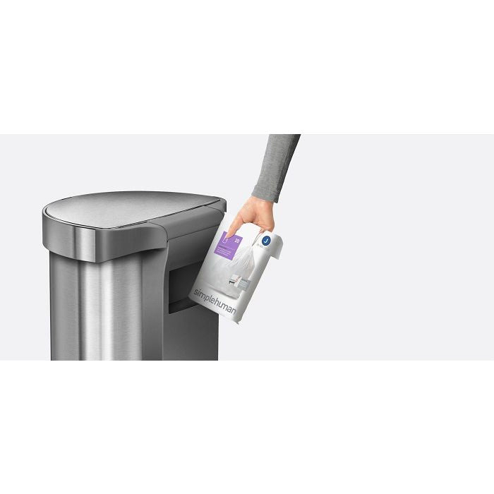 Simplehuman Semi Round Sensor Bin With Liner Pocket-Person holding a Simplehuman trash can liner next to a trash can on a white background