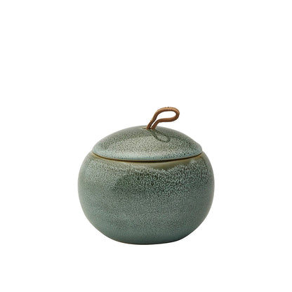 Green ceramic jar with textured surface and metallic handle on a white background