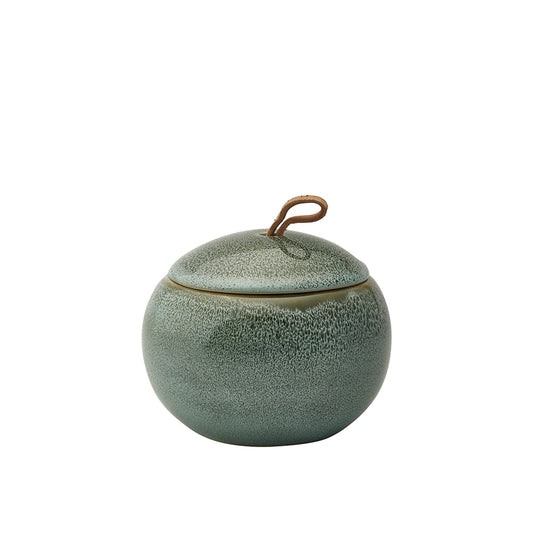 Green ceramic jar with textured surface and metallic handle on a white background