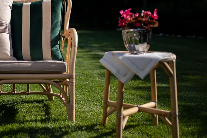 Amalfi Linen Napkin Set of 4-Wicker chair with striped cushions and a small table with flowers on a grassy area