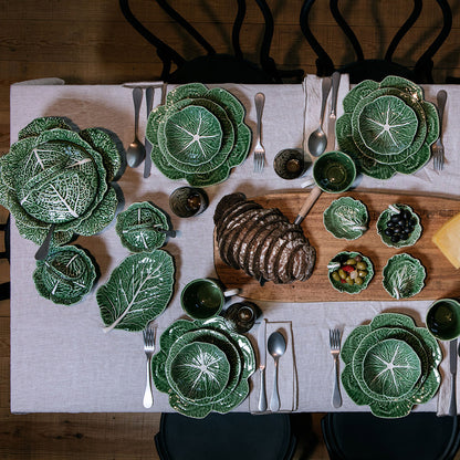 Bordallo Pinheiro Cabbage Chip & Dip Bowl-Dining table set with green leaf-patterned plates and a cutting board with bread and small dishes.
