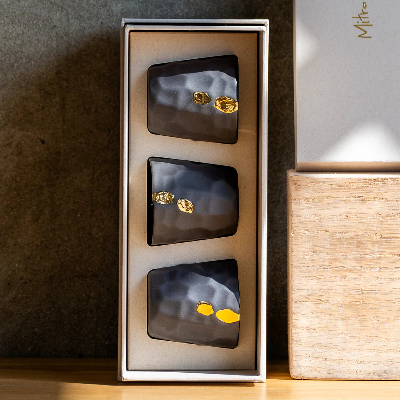 Set of black and gold Cawa Cups in a box on a wooden surface