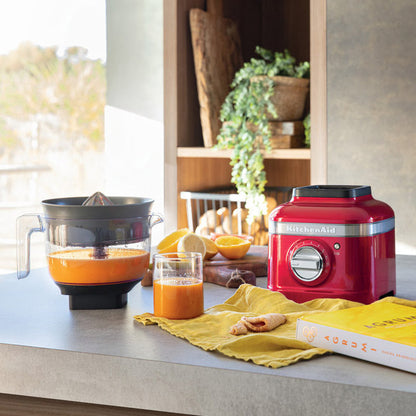Kitchen scene with a red KitchenAid mixer, orange juice, and a book on a countertop.