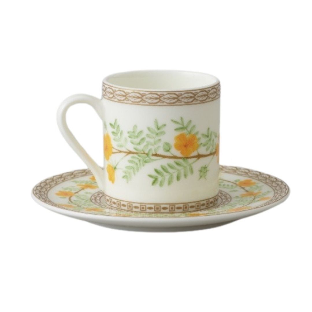 Collation formation curation A white ceramic cup with green and yellow floral patterns, accompanied by a matching saucer.